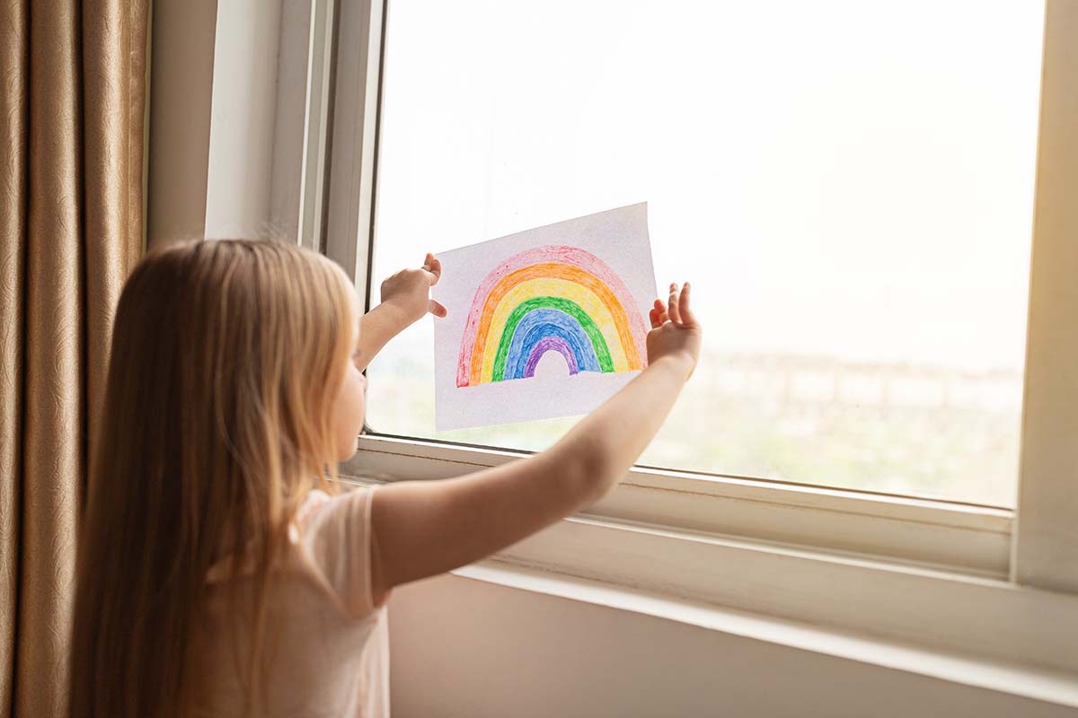 Child with rainbow in window
