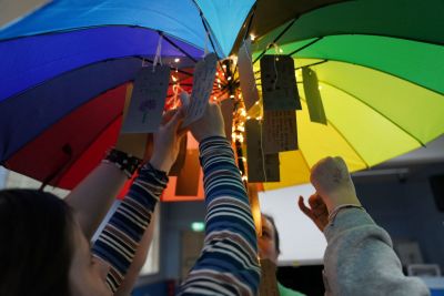 YW volunteers using a brightly coloured umbrella in their workshop.